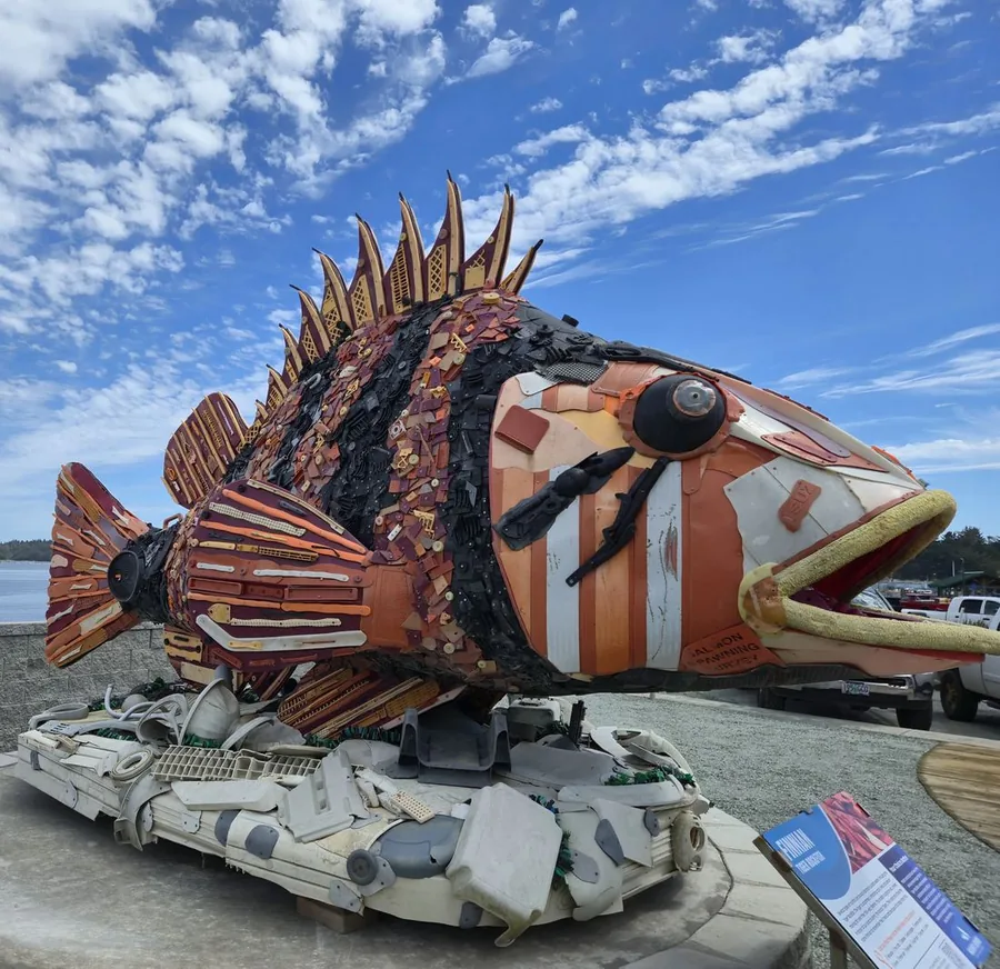 Washed Ashore sculpture of a giant orange and purple fish made entirely of recycled ocean plastic, standing at the Port of Bandon